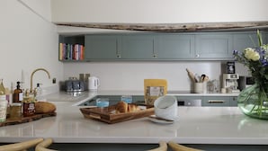 A modern kitchen with grey cabinets, a white countertop, and various kitchen appliances. - Beautifully presented dog friendly - The Barley Apartment (Cirencester)
