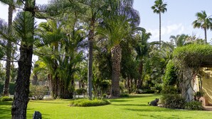 A lush garden with palm trees, a statue, and a well-maintained lawn. - Splendid Penina Country House Retreat (Portimão)