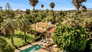 A villa with a swimming pool, surrounded by lush greenery and palm trees. - Splendid Penina Country House Retreat (Portimão)