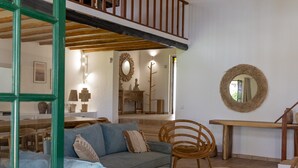 A spacious living area with a high ceiling, a wooden staircase, a dining table, and a sofa. - Splendid Penina Country House Retreat (Portimão)