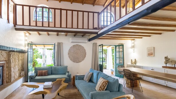 A spacious living area with a high ceiling, a built-in fireplace, a sofa set, and a dining area with a long table. - Splendid Penina Country House Retreat (Portimão)