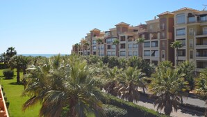 A multi-story hotel with balconies, located near a beach with palm trees. - Albatros 23 - Two Bedroom Apartment, Sleeps 5 (Punta del moral)
