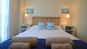 A hotel room with a large bed, two bedside tables, two wall-mounted lamps, and two paintings. - Albatros 23 - Two Bedroom Apartment, Sleeps 5 (Punta del moral)