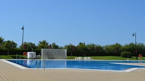 A swimming pool with a tiled deck, lifeguard chairs, and a fence. - Los Cisnes 13 - Two Bedroom Apartment, Sleeps 5 (Punta del moral)