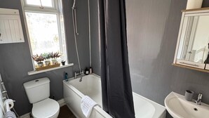 A bathroom with a bathtub, toilet, sink, and window with plants. - City Centre-4 Br-sleeps 7-garden-free Parking (Newcastle-upon-Tyne)