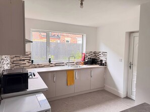 A modern kitchen with a window, a microwave, a toaster, and a kettle.