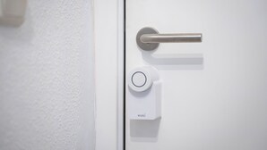 A white door with a metallic handle and a white electronic lock labeled "NUKI".