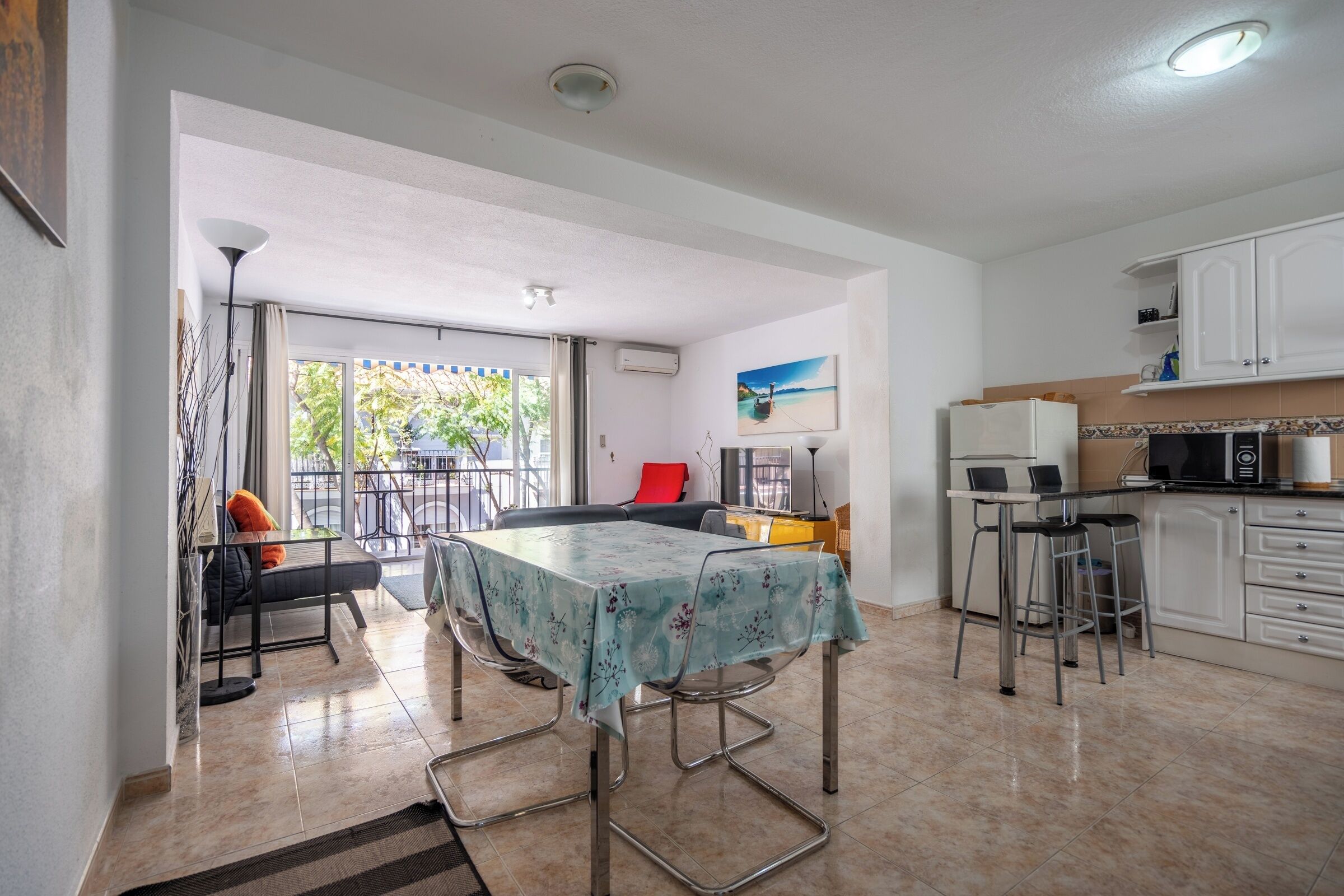A spacious kitchen with a dining area, a balcony, and a view of the outdoors.