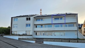 Een meerlaags woongebouw met een plat dak, zonnepanelen en een zichtbare antenne.