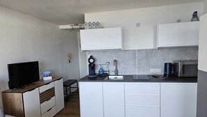 Een moderne keuken met witte kasten, een zwart aanrecht en een eethoek met houten details.