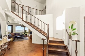 A spacious living area with a wooden staircase, a sofa set, and a view of the outdoors.