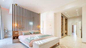 Une chambre à coucher moderne avec un grand lit, une table de chevet, une armoire et un dressing.