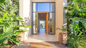 Une entrée moderne avec des portes en verre, un cadre de porte en bois et un chemin menant à un intérieur bien éclairé.