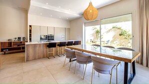 Une cuisine moderne dotée d’un îlot central, de tabourets de bar et d’une grande fenêtre offrant une vue sur l’extérieur.