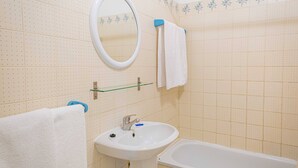 A bathroom with a white sink, a mirror, a bathtub, and a towel rack. - Apartament Sea View 8E (Portimão)