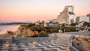 A coastal promenade with a patterned walkway, a beach, and buildings in the background. - Apartament Sea View 8E (Portimão)