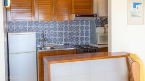 A kitchen with wooden cabinets, a gas stove, a microwave, and patterned backsplash tiles. - Apartament Sea View 8E (Portimão)