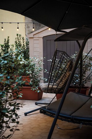 A hanging chair under a canopy, surrounded by potted plants and a tiled floor. - Salvator Rosa Rooms (Naples)
