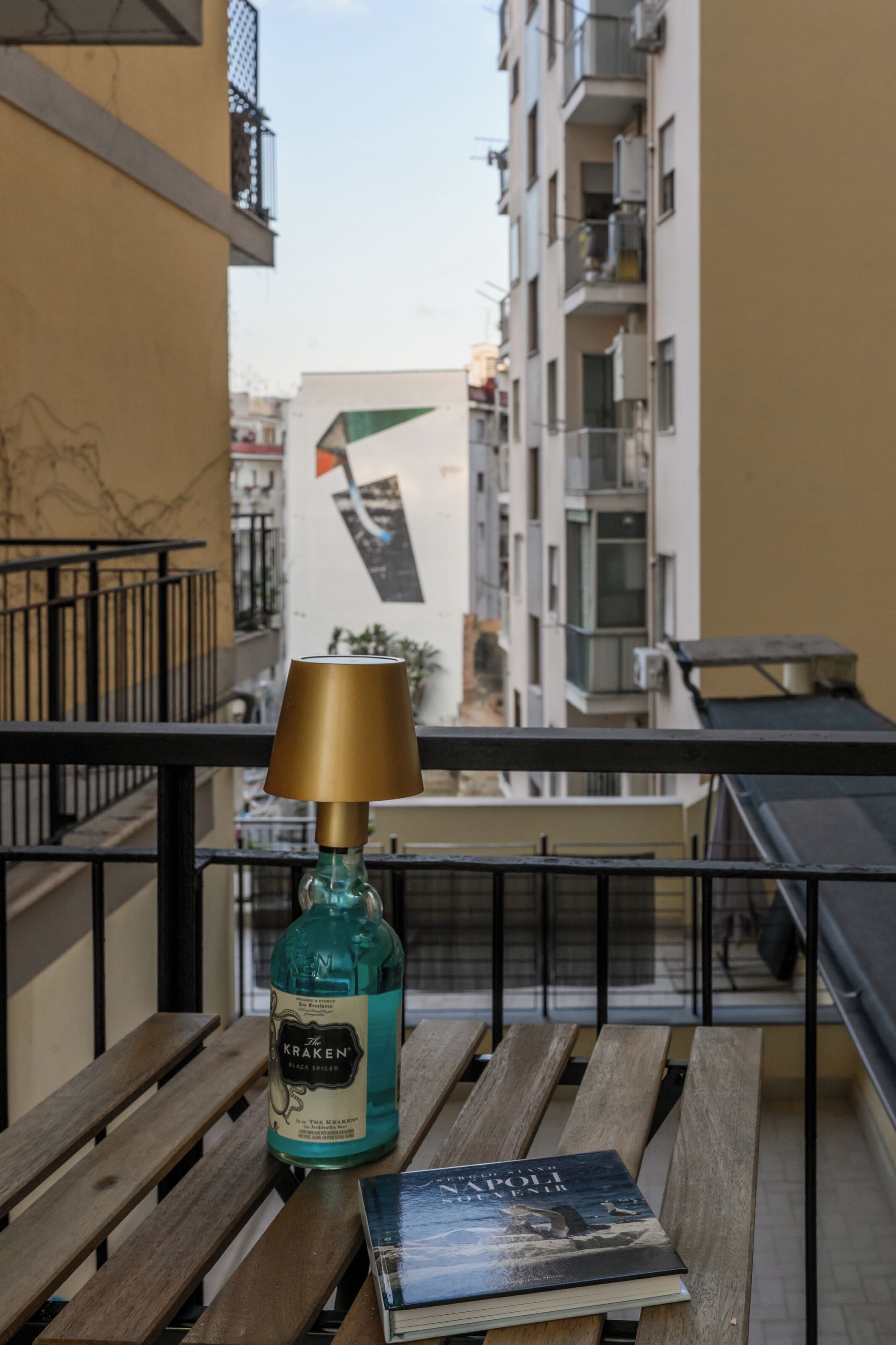 A balcony with a wooden table, a bottle of Kraken Black Spiced liquor, and a book titled "The Napoleonic Wars".