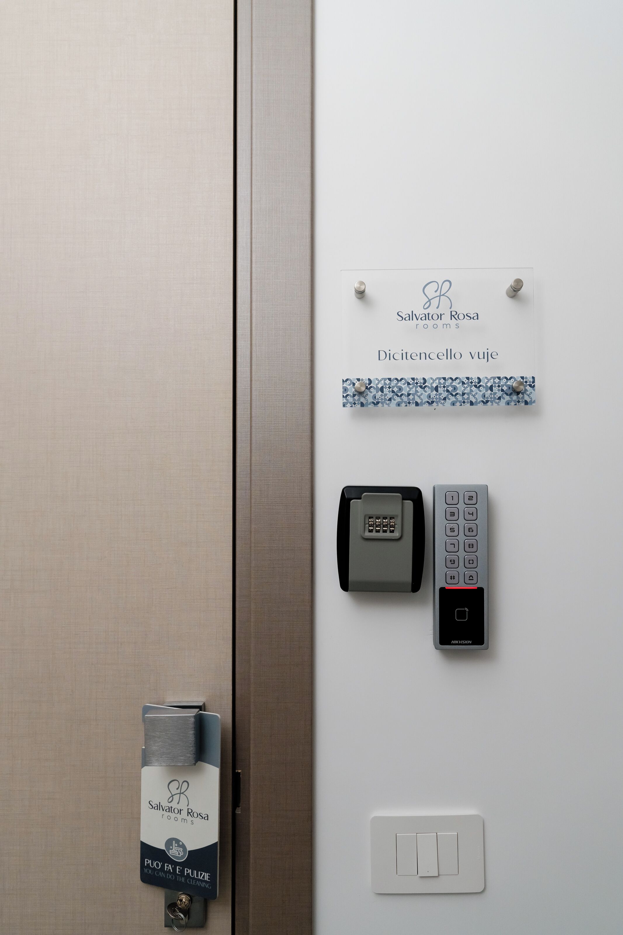 A hotel room door with a key card reader, a key card, a key fob, a keyless entry keypad, and a light switch.
