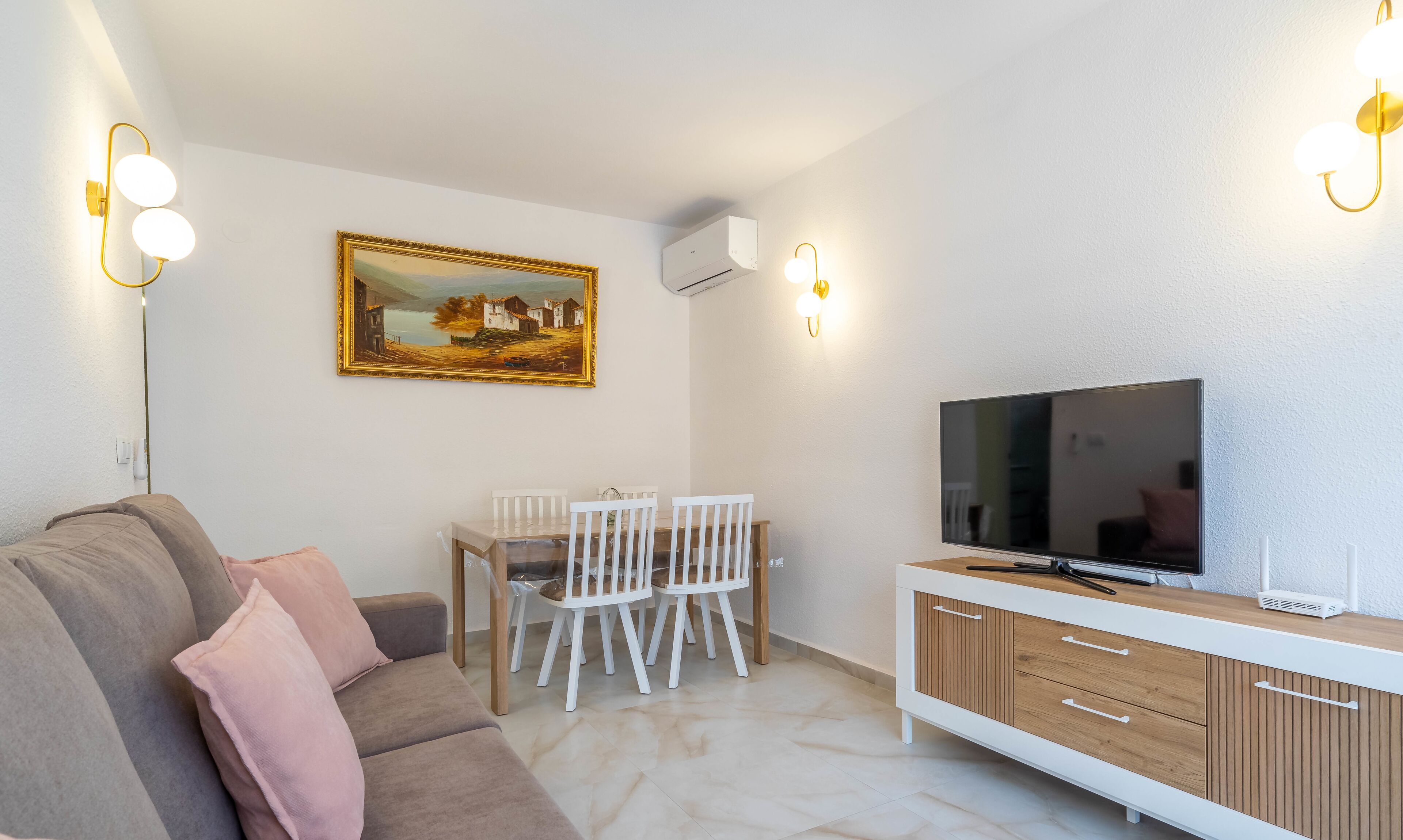Un salon moderne avec un canapé, une table à manger et des chaises, un téléviseur et un tableau accroché au mur.