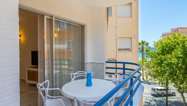 A balcony with a white table and chairs, a blue railing, and a view of the sea. - Arenal Mar Inftour (Calp)
