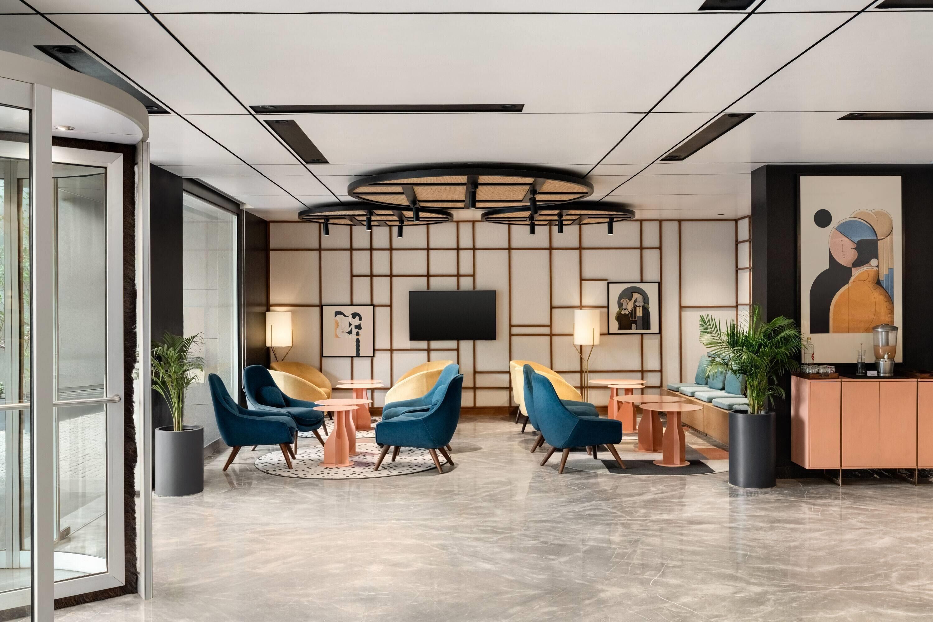 Een moderne lobby met een televisie, zithoek en een groot schilderij.