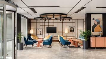 Een moderne lobby met een televisie, zithoek en een groot schilderij.