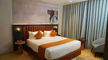 Habitación de hotel con una cama grande, cabecera, mesita de noche, una silla y una pared con diseño decorativo.