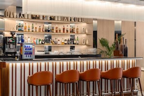 Eine Bar mit mehreren Regalen voller Spirituosenflaschen, einem Getränkeautomaten und Barhocker.