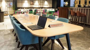 Um centro de negócios com uma mesa comprida, cadeiras azuis e um laptop.