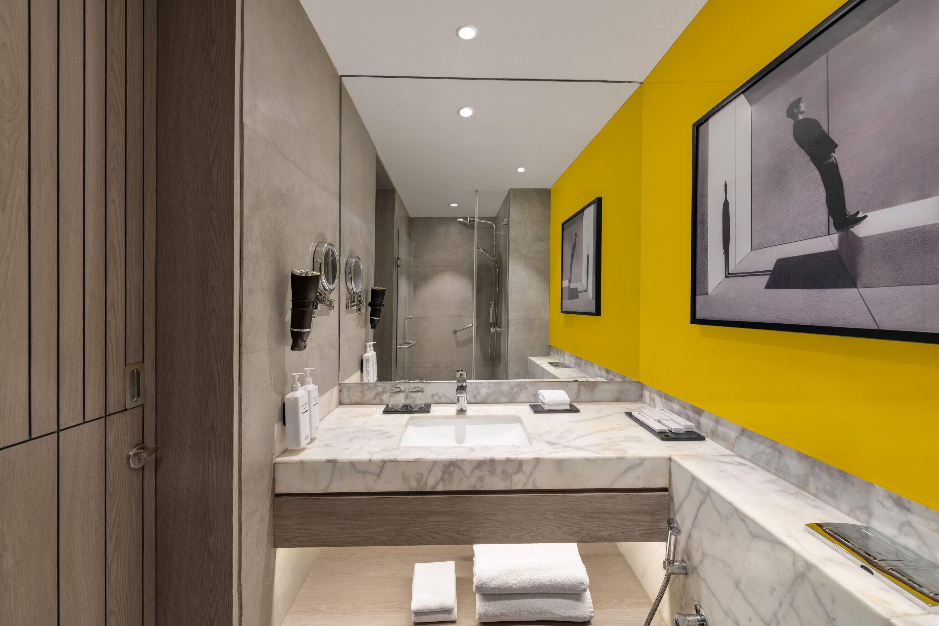 A modern bathroom with a large mirror, a sink, and a shower.