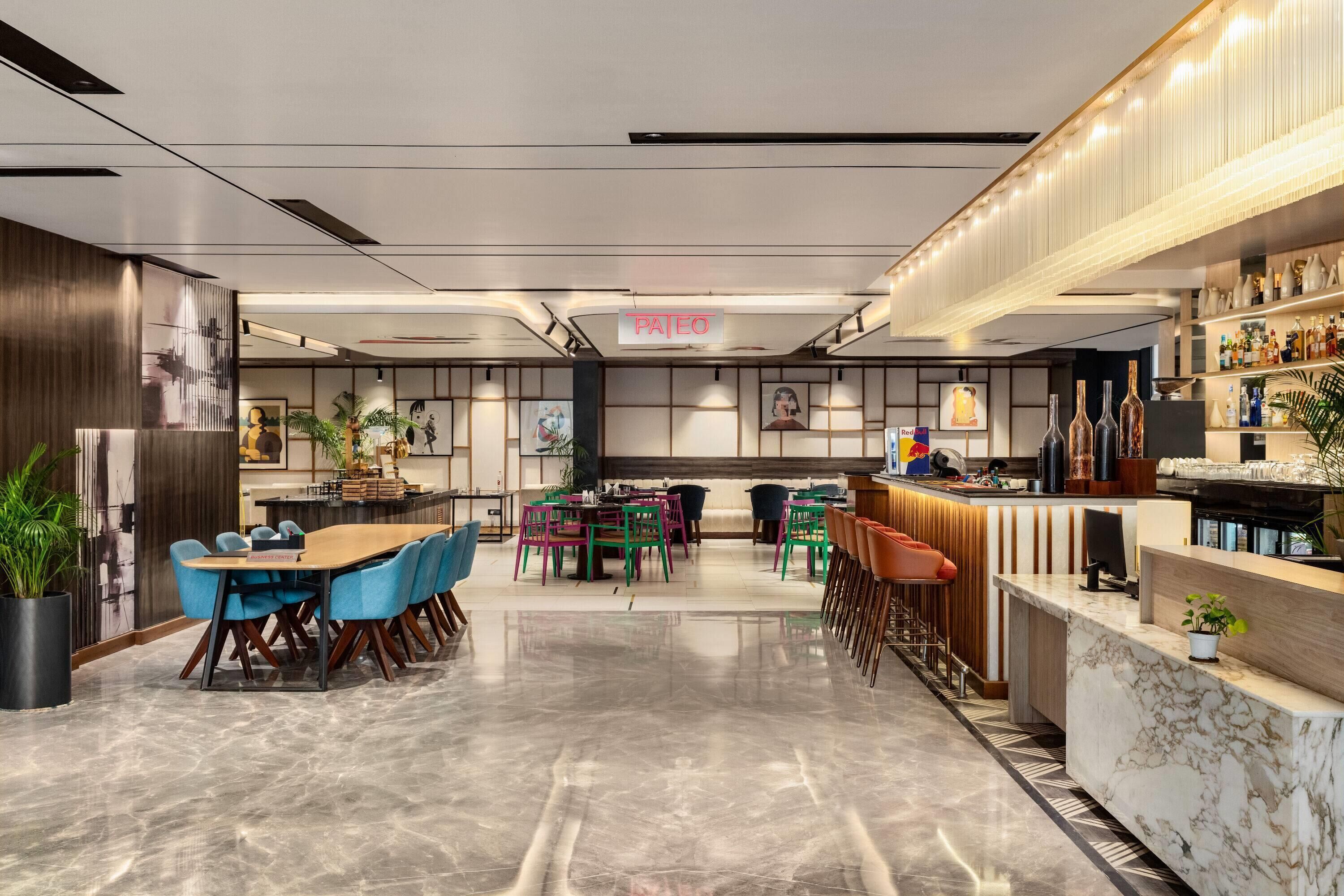 Un moderno vestíbulo de hotel con una recepción, área de descanso y un bar.