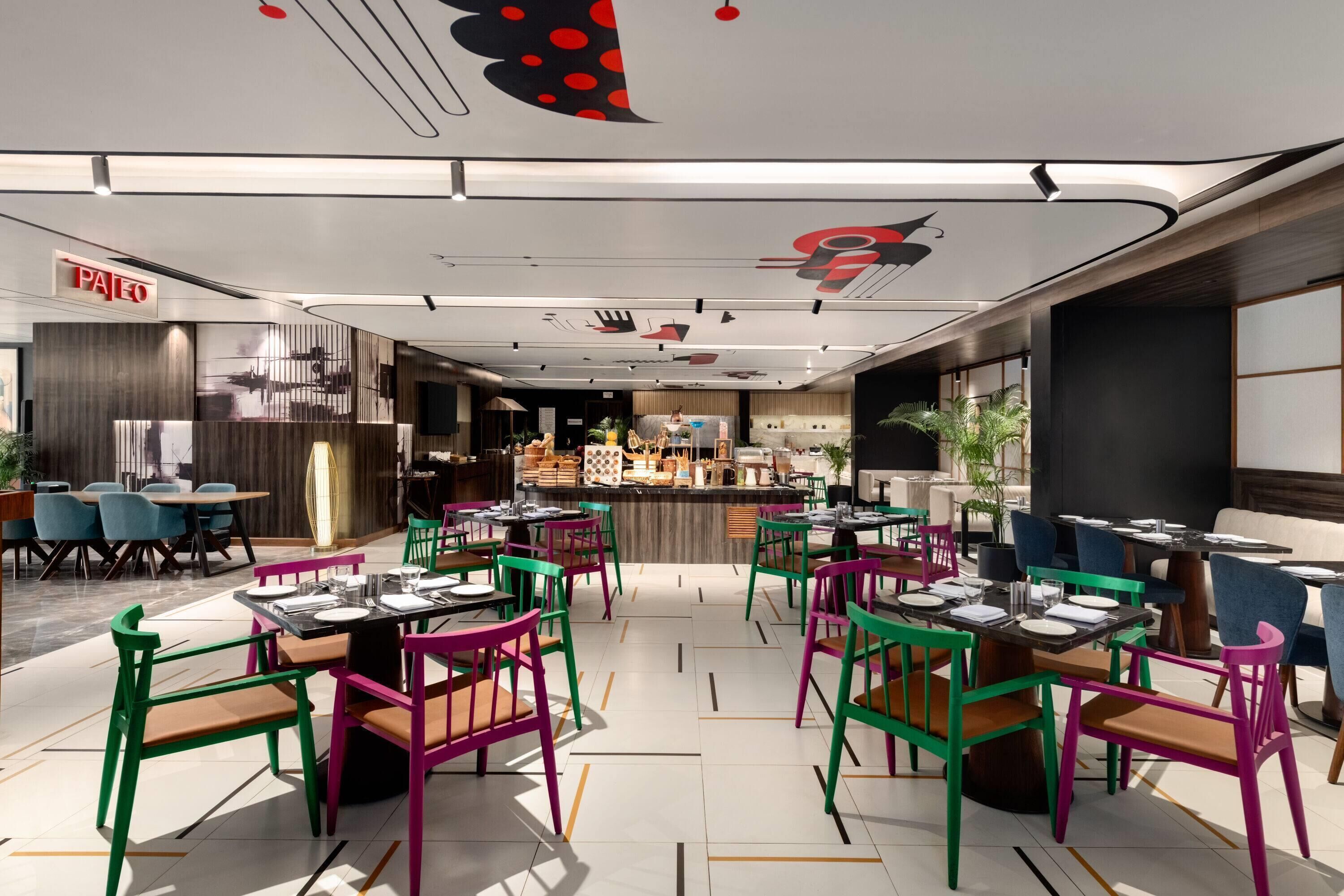 Un ristorante con sedie e tavoli colorati, una zona bar e un moderno design del soffitto.