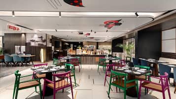 A restaurant with colorful chairs and tables, a bar area, and a modern ceiling design.