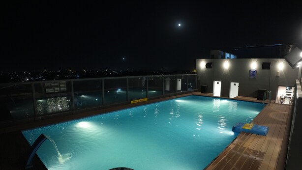 Una piscina con muelle de madera, un flotador salvavidas y una luna en el cielo.