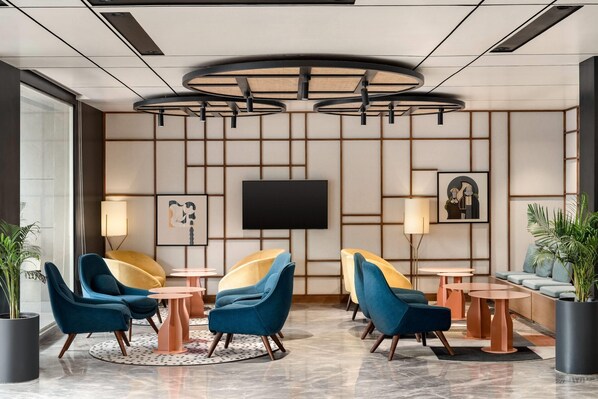 A modern lobby with seating areas, a flat-screen TV, and a large potted plant. - Ramada Encore By Wyndham Chandigarh Zirakpur (Zirakpur)
