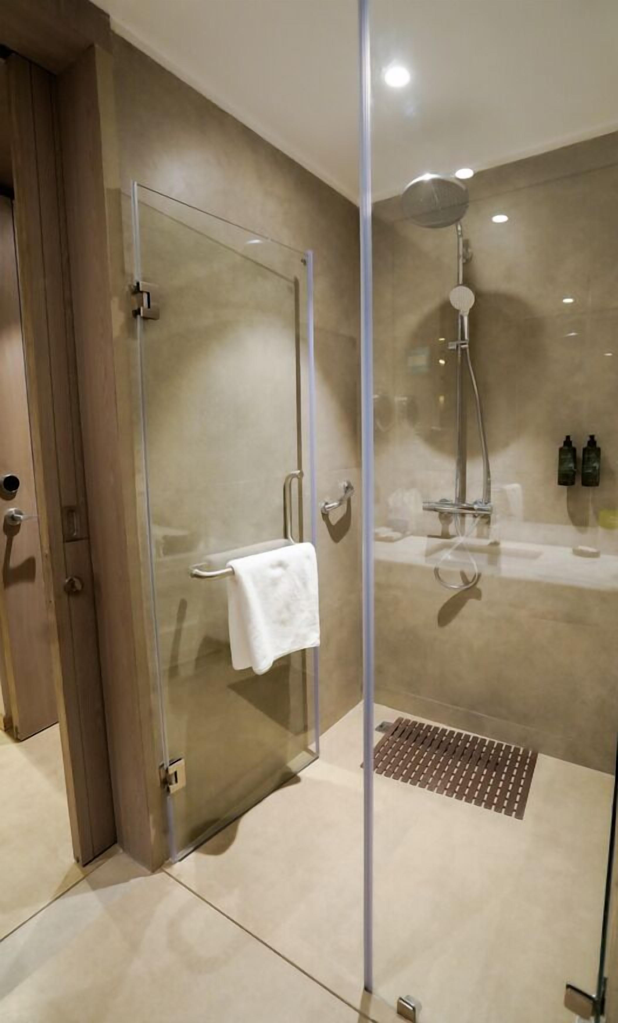 Ein modernes Badezimmer mit einer Duschkabine, einem weißen Handtuch, das an der Tür hängt, und einer Handbrause.