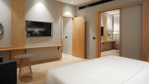 A modern hotel room with a bed, a TV, a small round table, and a mirror. - Ramada by Wyndham Ranchi (Ranchi)