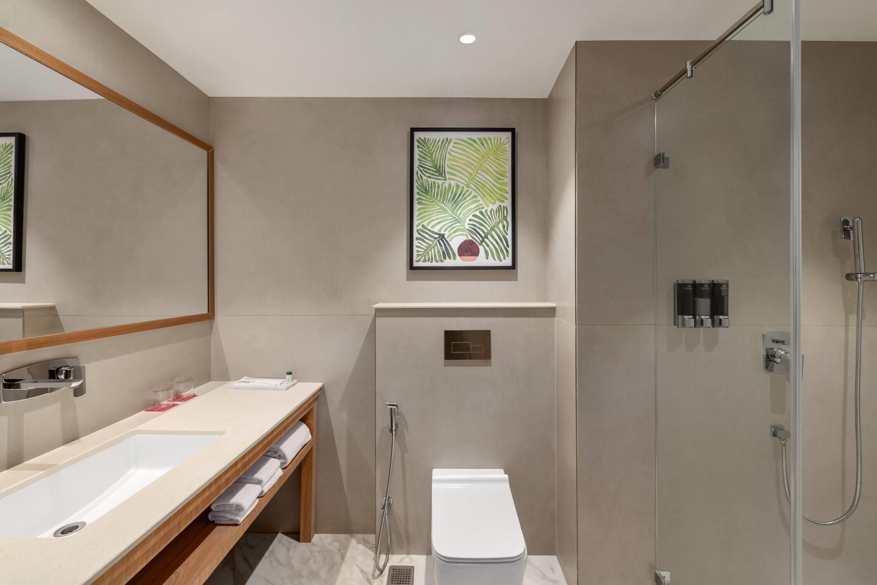 Ein modernes Badezimmer mit großem Spiegel, Waschbecken, Toilette und Dusche.