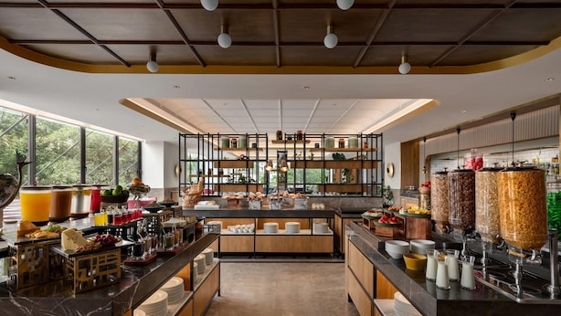 A modern breakfast bar with a variety of food options and a large window providing a view of the outdoors. - Ramada by Wyndham Ranchi (Ranchi)