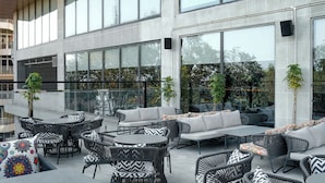 An outdoor seating area with wicker furniture and a large windowed wall. - Ramada by Wyndham Ranchi (Ranchi)