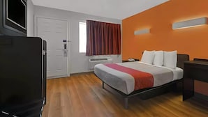 Ein Hotelzimmer mit Bett, Fernseher, Schreibtisch und Klimaanlage.