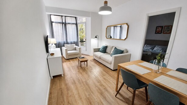 Una sala de estar moderna con comedor, un sofá, una mesa de centro y una mesa de comedor con sillas.