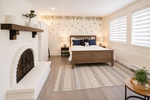 Un dormitorio con cama de madera, chimenea, pared con diseño y ventana con persianas.