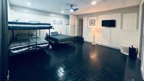A room with bunk beds, a flat-screen TV, and a ceiling fan.