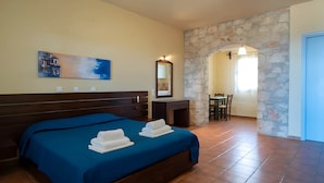 A hotel room with a bed, a desk, and a stone wall. - Samos Gem With Private Pool - Mantilada Village (Samos)