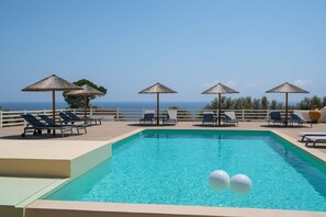 A pool area with lounge chairs and umbrellas, overlooking a body of water.