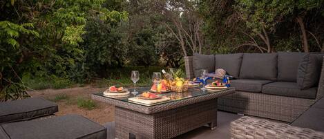 An outdoor seating area with wicker furniture, a glass-top table, and a sofa.