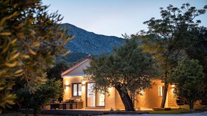 A modern house with a patio, surrounded by trees and a mountain in the background. - Seaside Villa Angel - Samos Cozy Getaway (Samos)